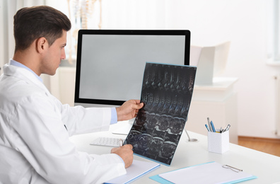 Photo of Orthopedist examining X-ray picture at desk in clinic