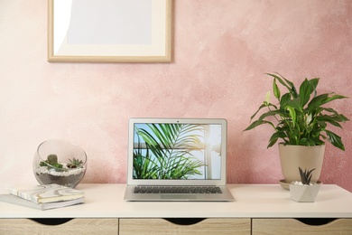 Houseplants and laptop on table in office interior