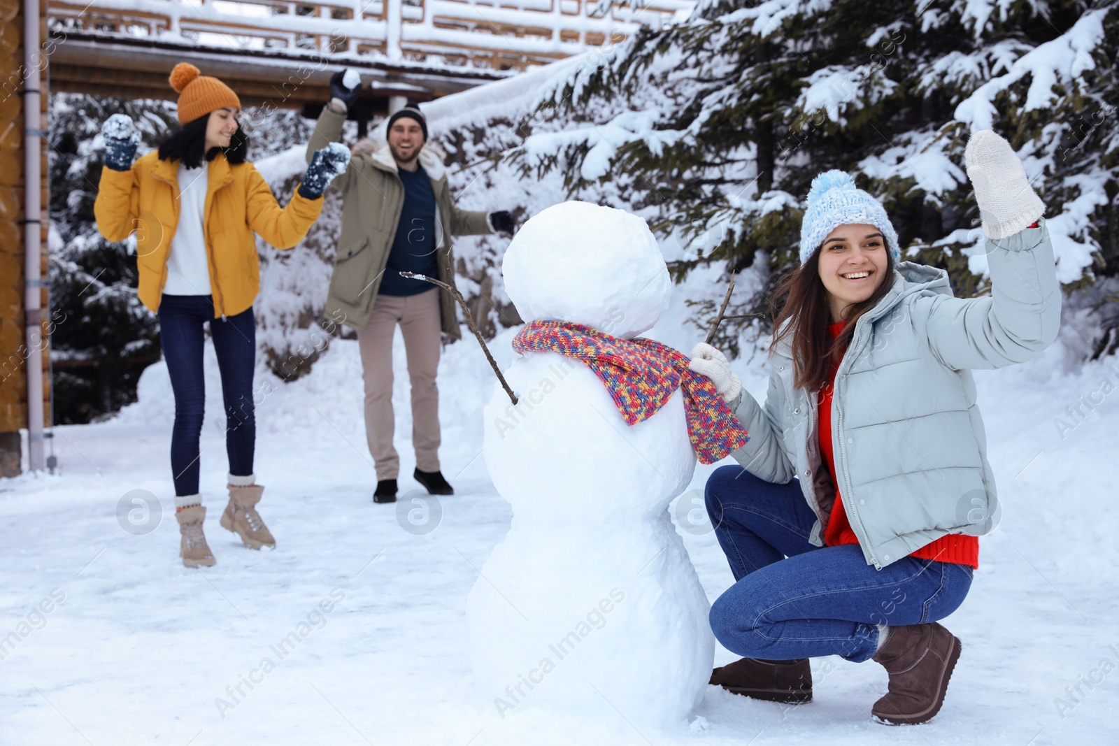 Photo of Happy friends making snowman outdoors. Winter vacation