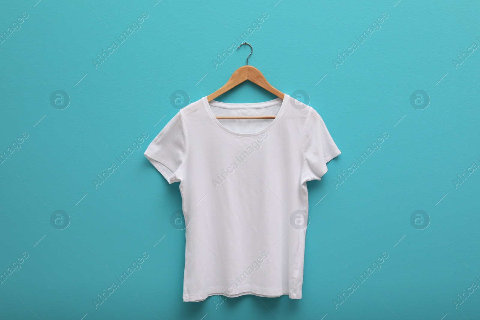 Photo of Hanger with blank t-shirt on color background. Mockup for design