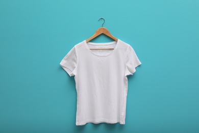 Photo of Hanger with blank t-shirt on color background. Mockup for design