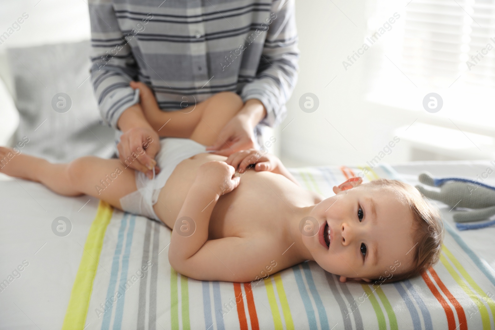 Photo of Mother changing baby's diaper on table at home