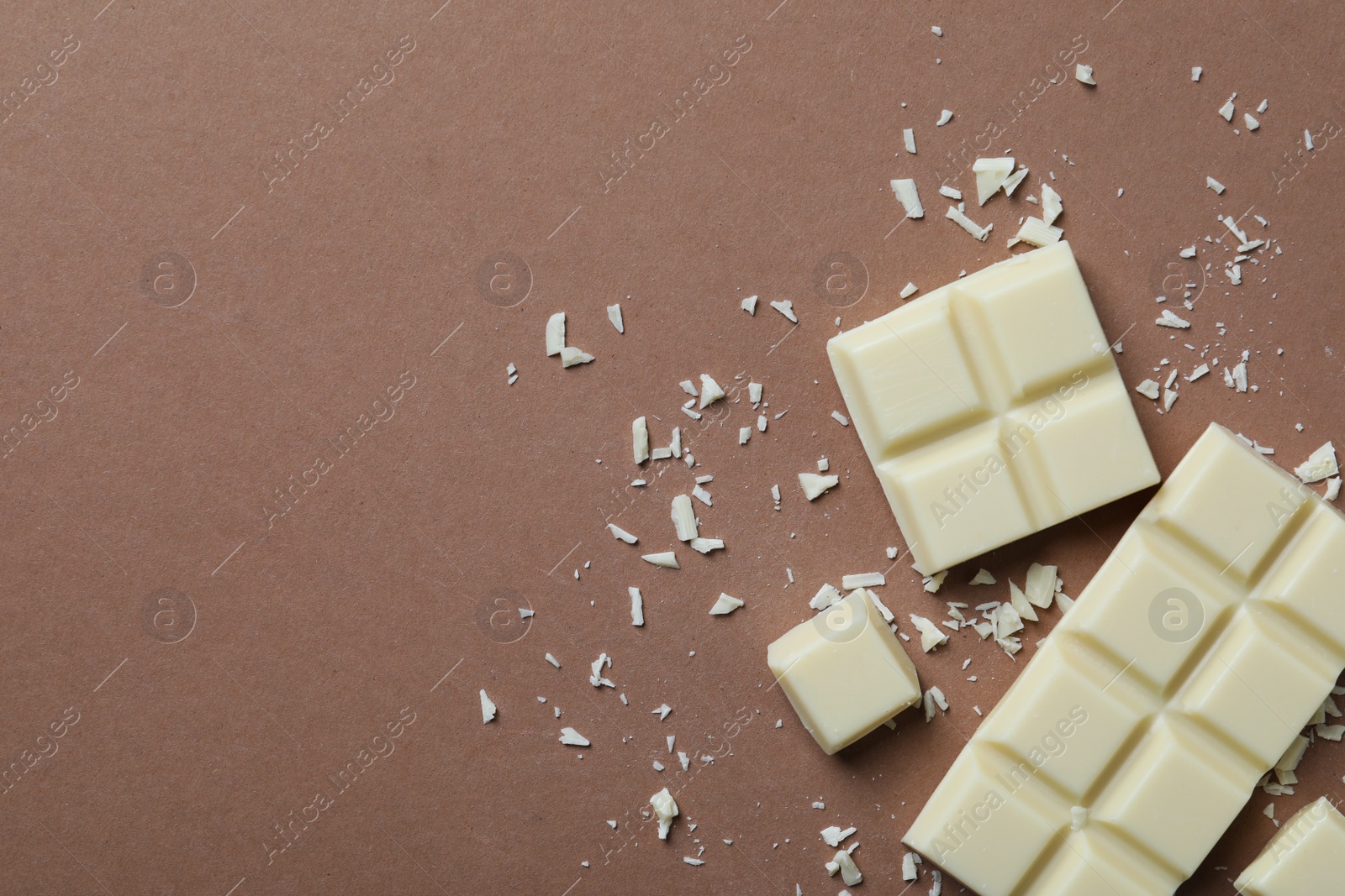 Photo of Tasty white chocolate on brown background, flat lay. Space for text