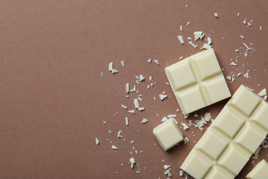 Photo of Tasty white chocolate on brown background, flat lay. Space for text