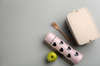 Photo of Thermos, lunch box with cutlery and apple on light grey background, flat lay. Space for text