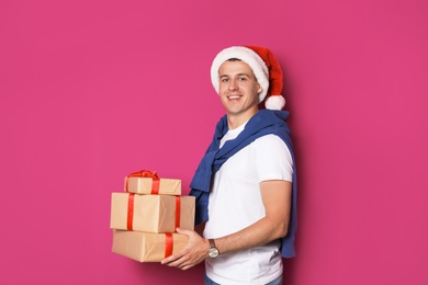 Photo of Young man with Christmas gifts on color background