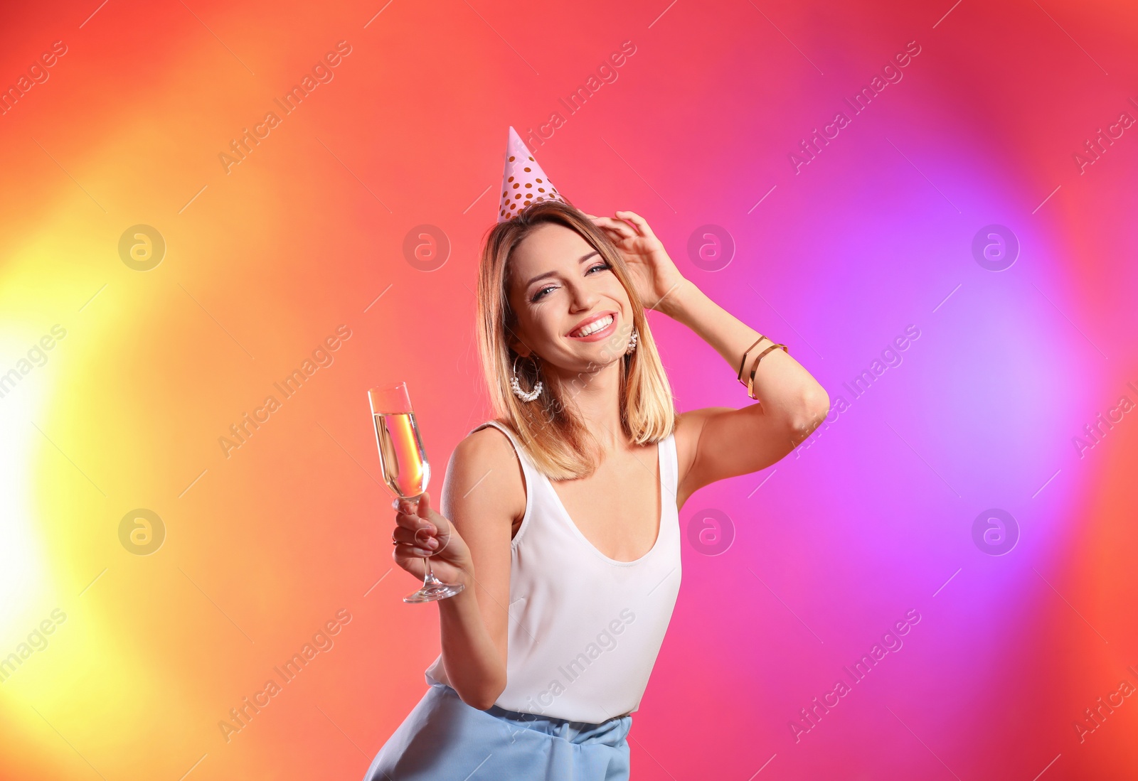 Photo of Portrait of happy woman with party hat and champagne in glass on color background