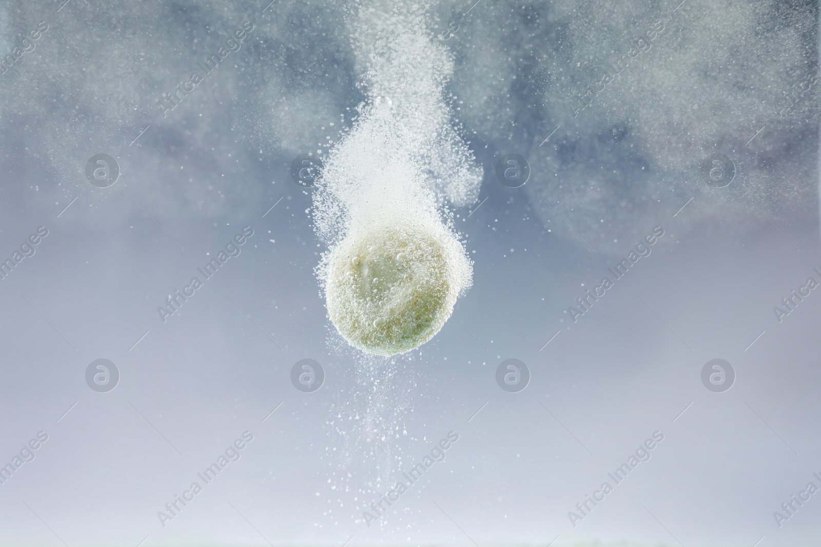 Photo of Effervescent pill dissolving in water on light background, closeup