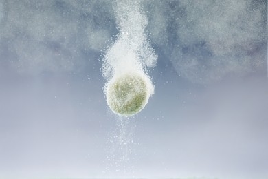 Effervescent pill dissolving in water on light background, closeup