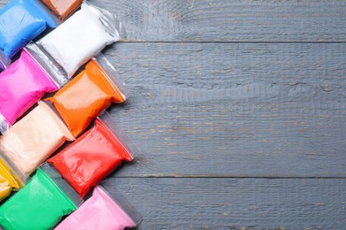 Photo of Many packages of different colorful plasticine on grey wooden table, flat lay. Space for text