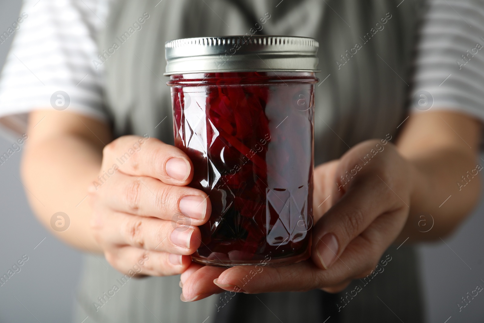 Photo of Woman holding glass jar with pickled beets, closeup