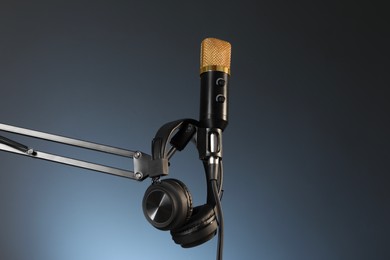Stand with microphone and headphones on dark background, low angle view. Sound recording and reinforcement