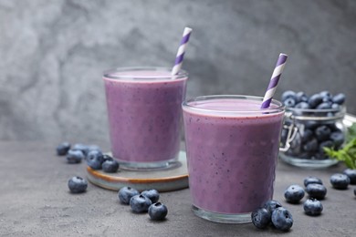 Tasty blueberry smoothie with fresh berries on grey table. Space for text