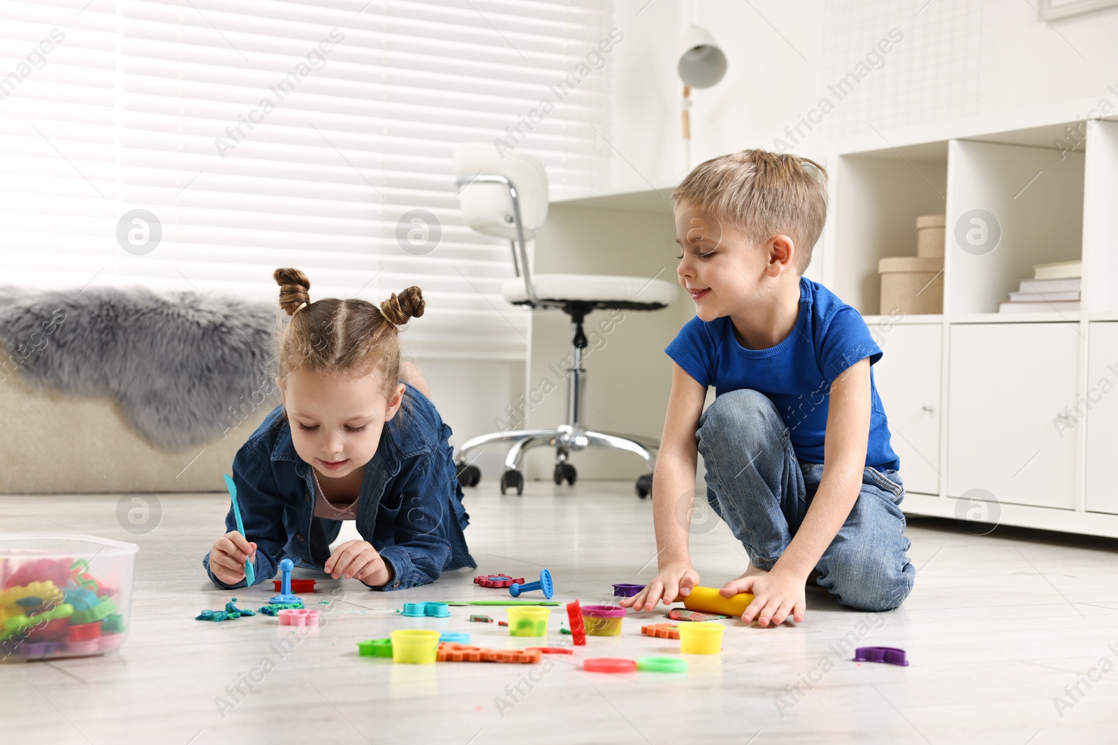 Photo of Cute little children playing on warm floor at home. Heating system