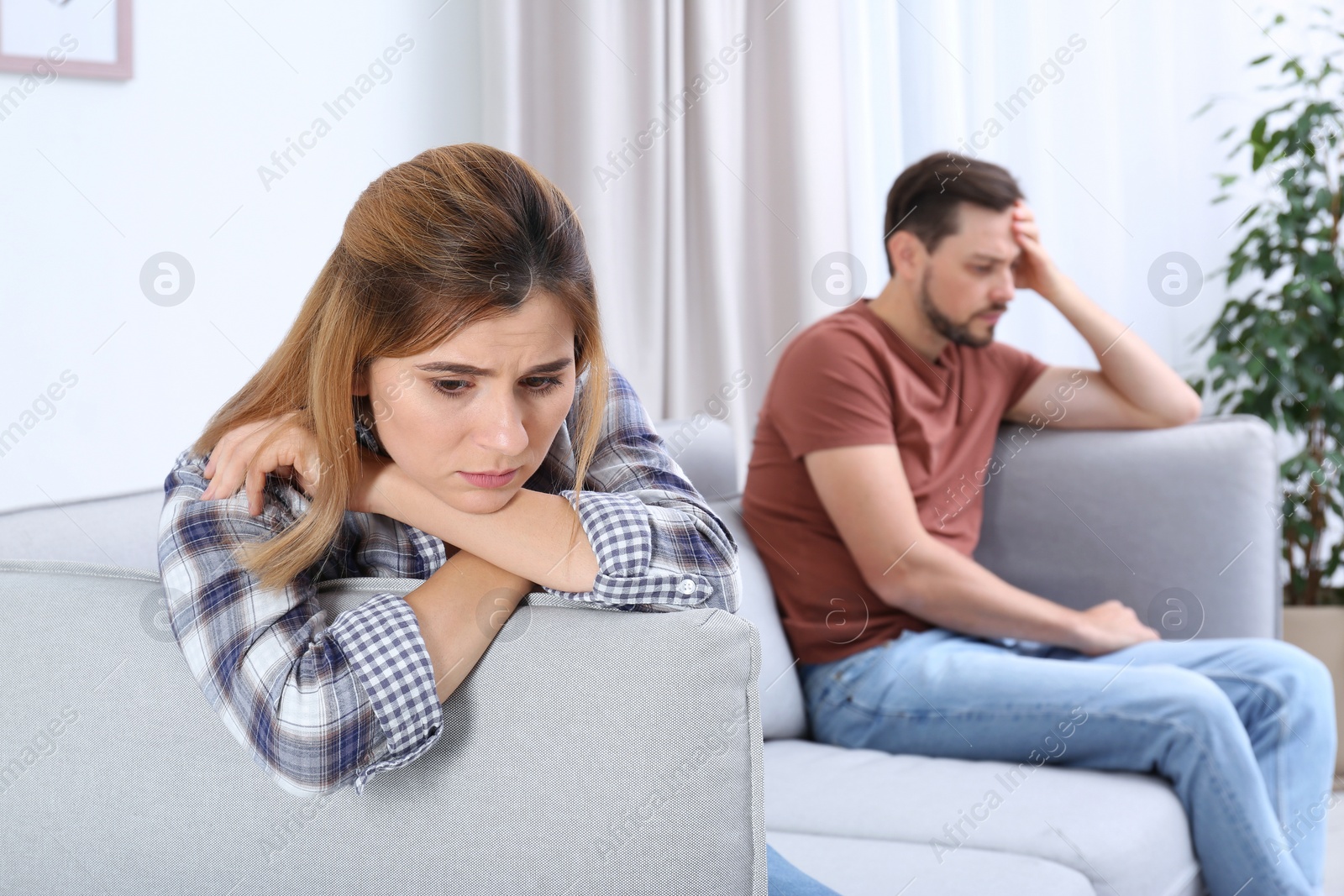 Photo of Couple ignoring each other after argument in living room. Relationship problems