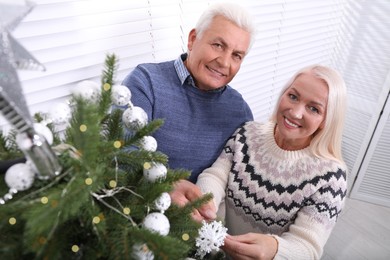 Happy mature couple decorating Christmas tree at home, above view