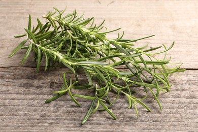 Photo of Aromatic green rosemary sprigs on wooden table, closeup