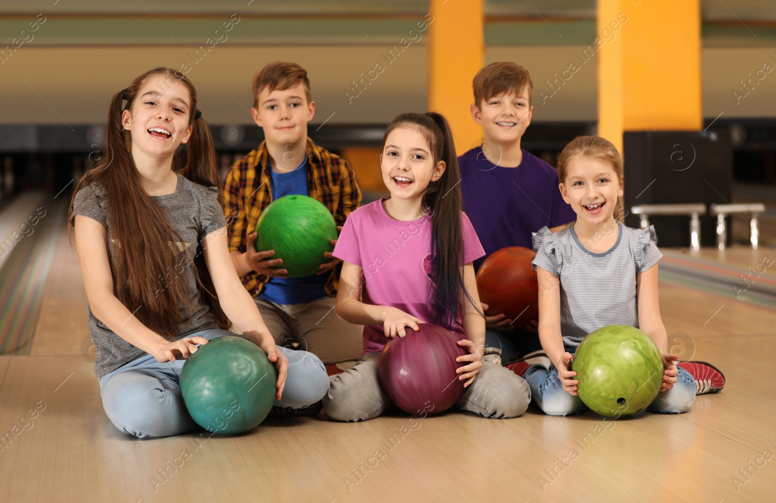 Photo of Happy children with balls in bowling club