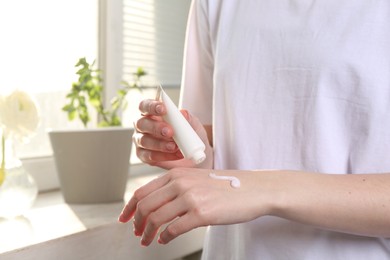 Woman applying hand cream at home, closeup