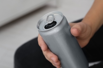 Man holding open aluminum can on blurred background, closeup. Space for design