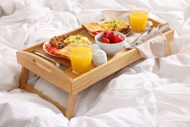 Photo of Good morning. Tray with tasty breakfast on bed