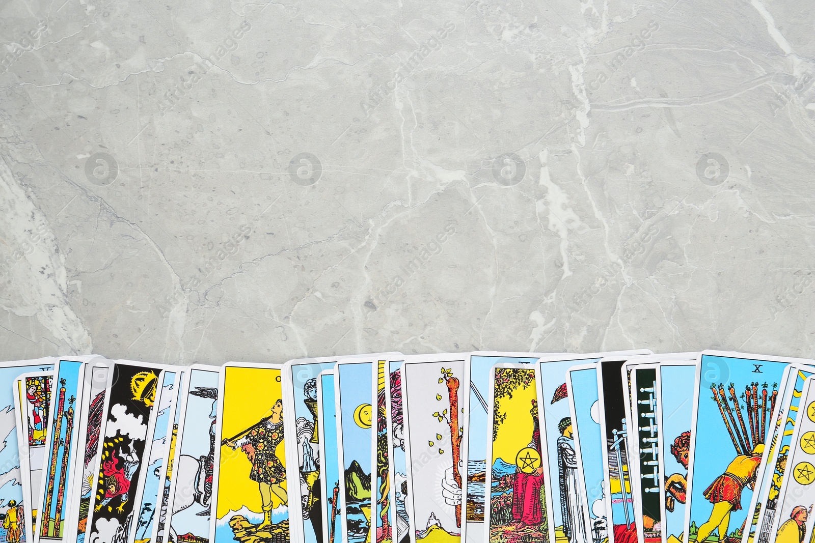 Photo of Tarot cards on light grey marble table, top view. Space for text