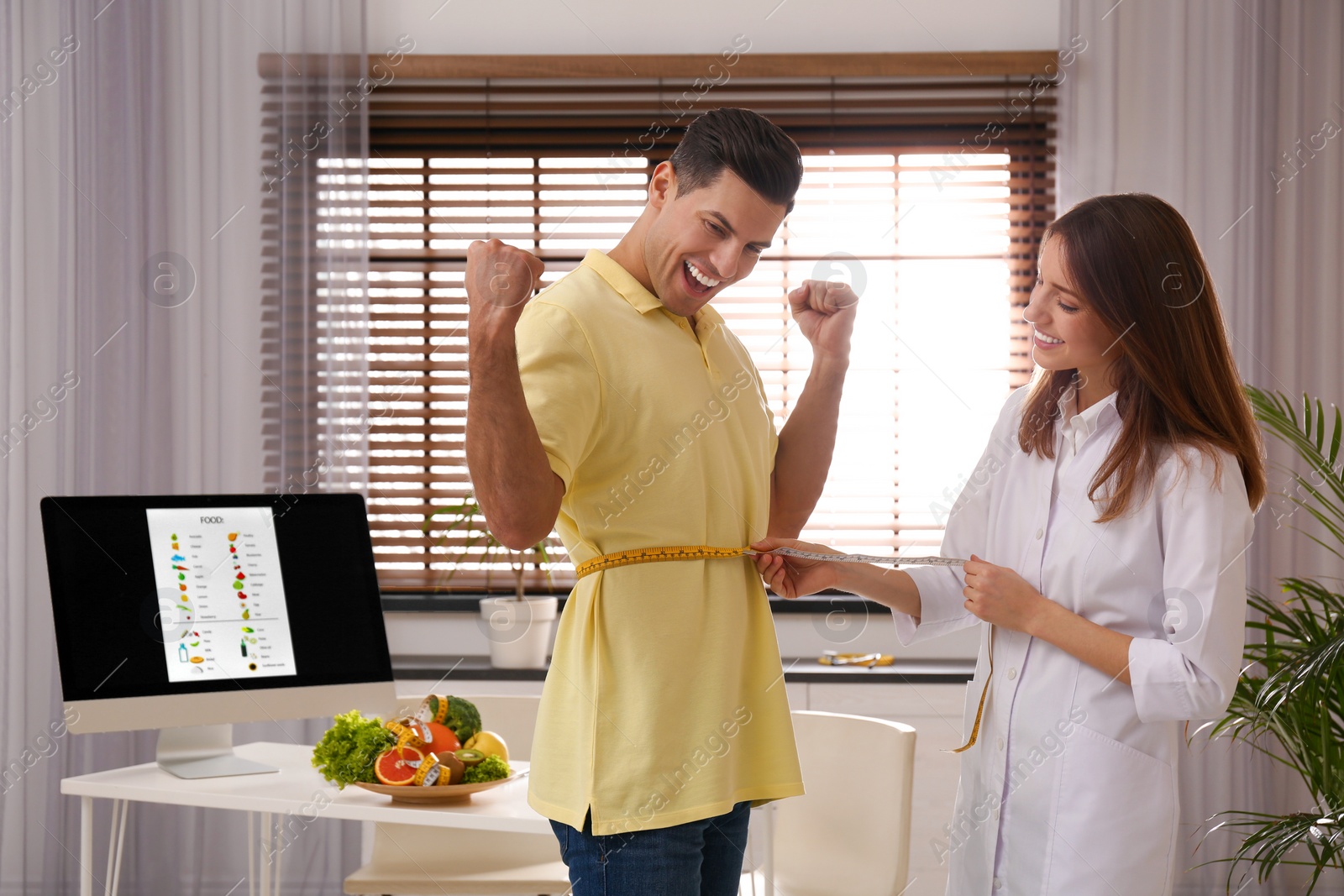 Photo of Young nutritionist measuring patient's waist in clinic