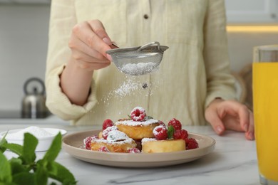 Woman sieving powdered sugar on cottage cheese pancakes at white table, closeup