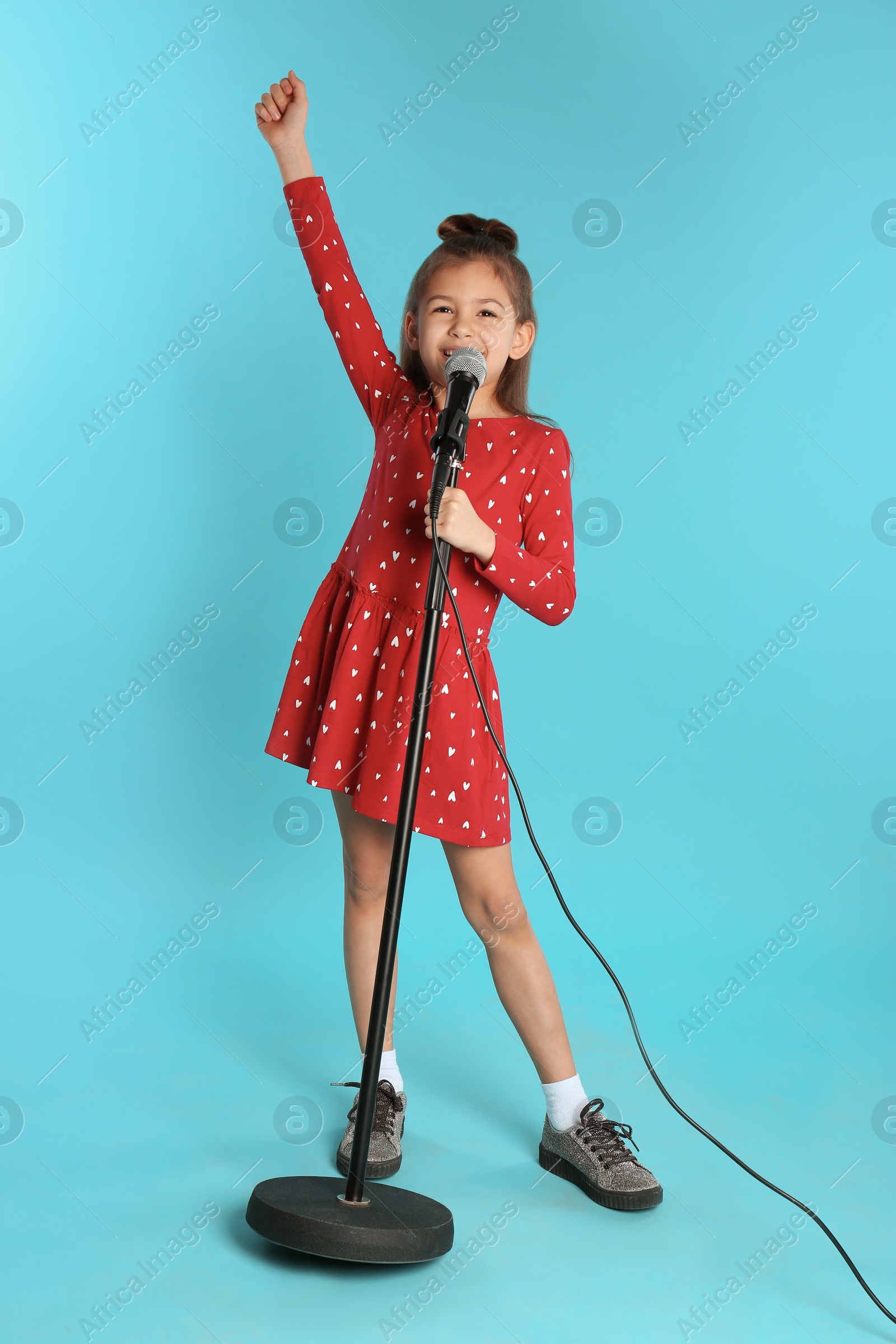 Photo of Cute funny girl with microphone on color background