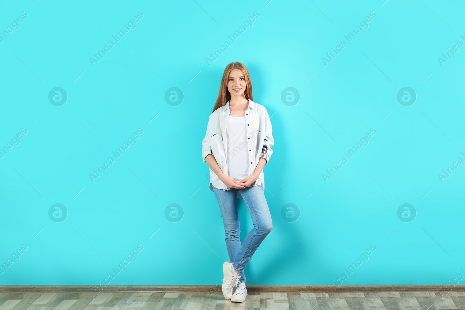 Photo of Young woman in stylish jeans near color wall