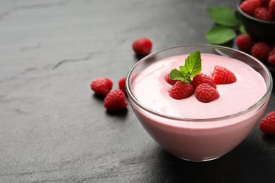 Photo of Delicious raspberry mousse with mint on black table, space for text