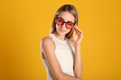 Photo of Beautiful woman in stylish sunglasses on yellow background