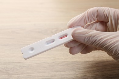 Photo of Doctor holding disposable Covid-19 express test at wooden table, closeup