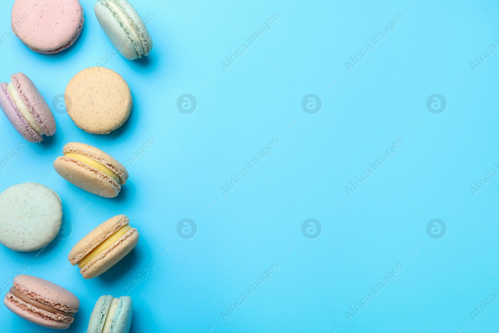 Photo of Delicious colorful macarons on light blue background, flat lay. Space for text