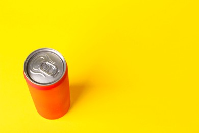 Photo of Energy drink in orange can on yellow background, above view. Space for text