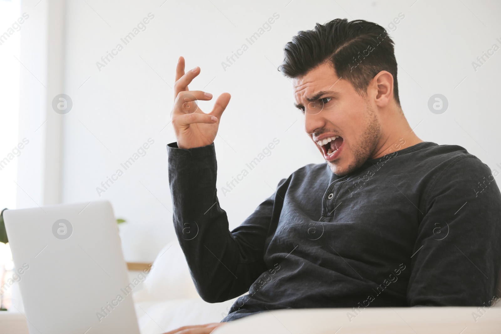 Photo of Emotional man working with laptop at home