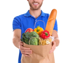 Photo of Delivery man holding paper bag with food products on white background, closeup