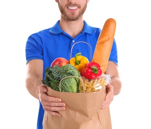 Delivery man holding paper bag with food products on white background, closeup