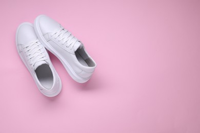 Photo of Pair of stylish white sneakers on pink background, top view. Space for text