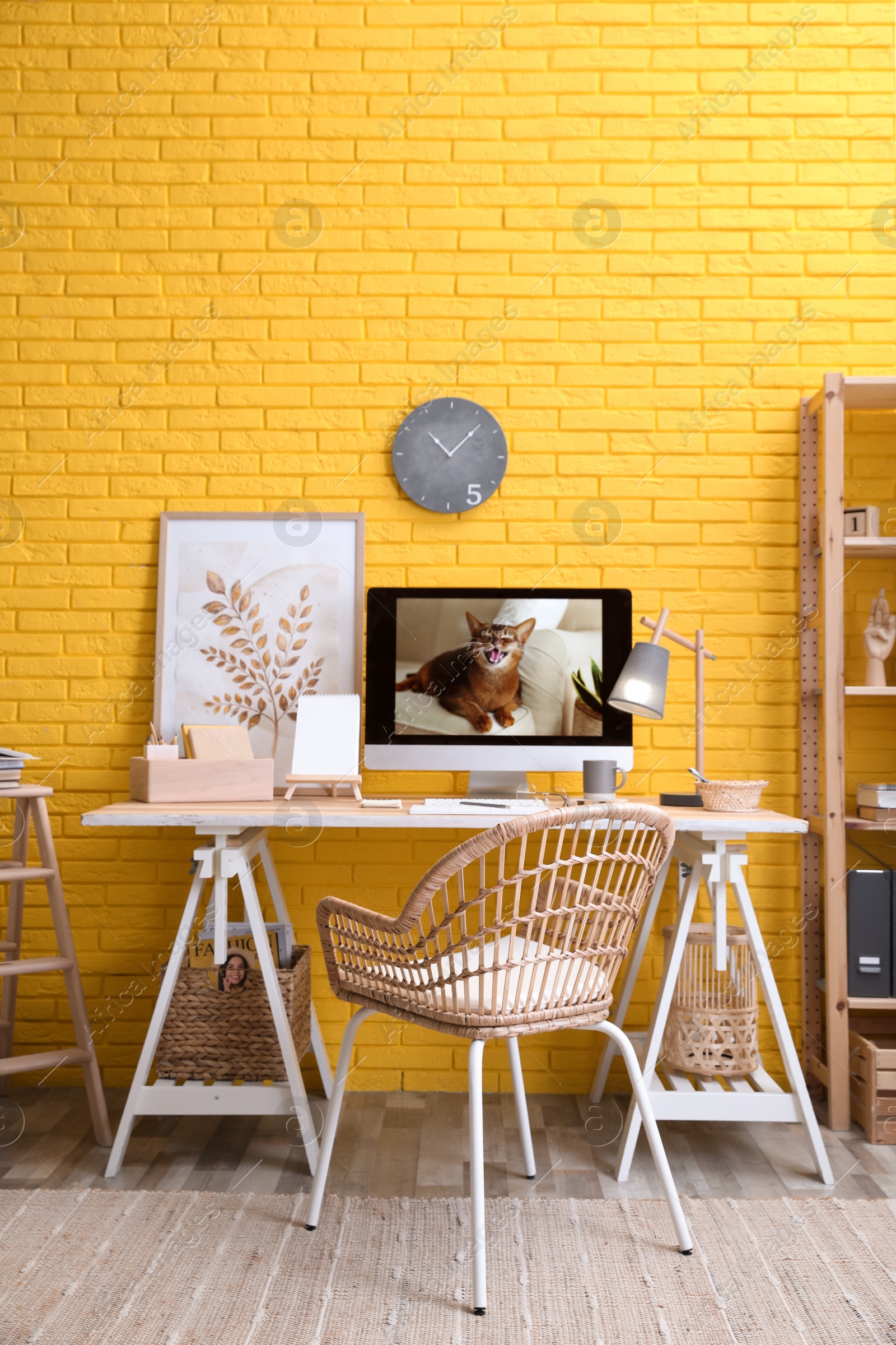 Photo of Stylish home office interior with comfortable workplace near yellow brick wall