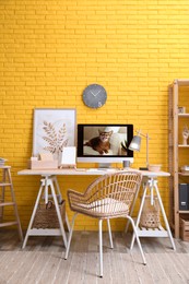 Photo of Stylish home office interior with comfortable workplace near yellow brick wall