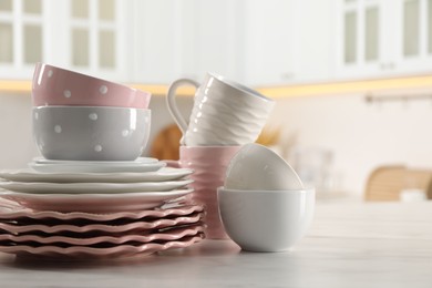 Many different clean dishware and cups on white marble table in kitchen