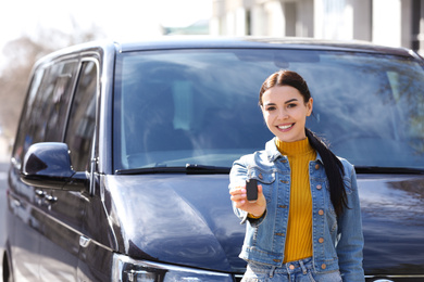 Photo of Young woman with key near car on city street. Buying new auto