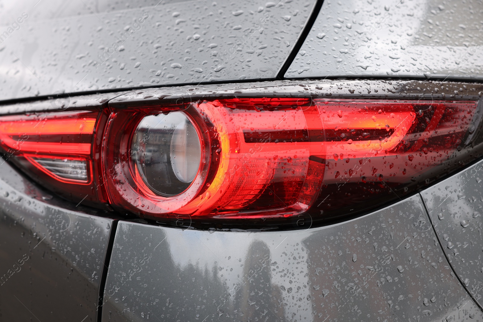 Photo of Car with switched on tail light in drops of water, closeup