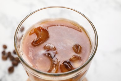 Photo of Refreshing iced coffee with milk in glass on white table, closeup