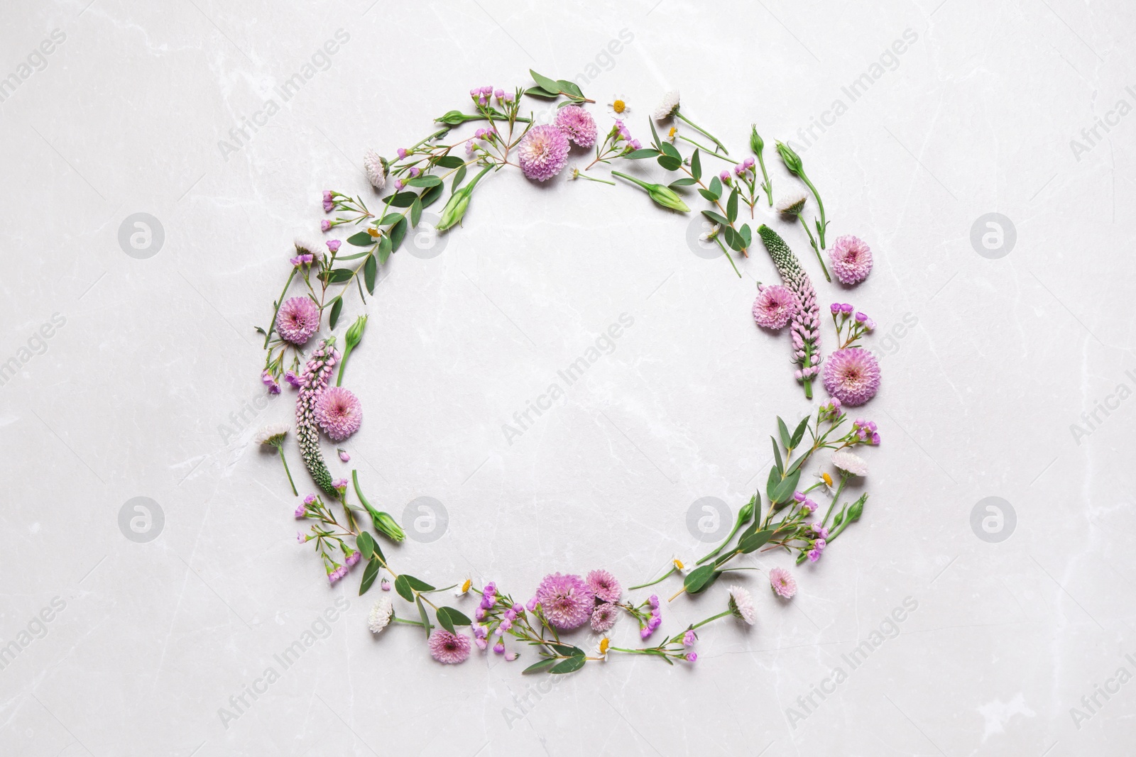 Photo of Wreath made of beautiful flowers and green leaves on light grey marble background, flat lay. Space for text