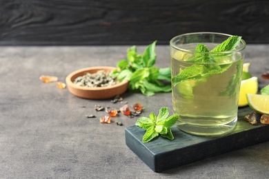 Photo of Glass with hot aromatic mint tea, fresh leaves and lime on table