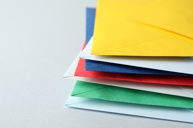 Stack of colorful paper envelopes on light background, closeup