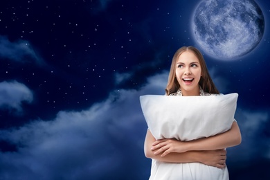 Image of Beautiful woman holding pillow and night starry sky with full moon on background. Bedtime