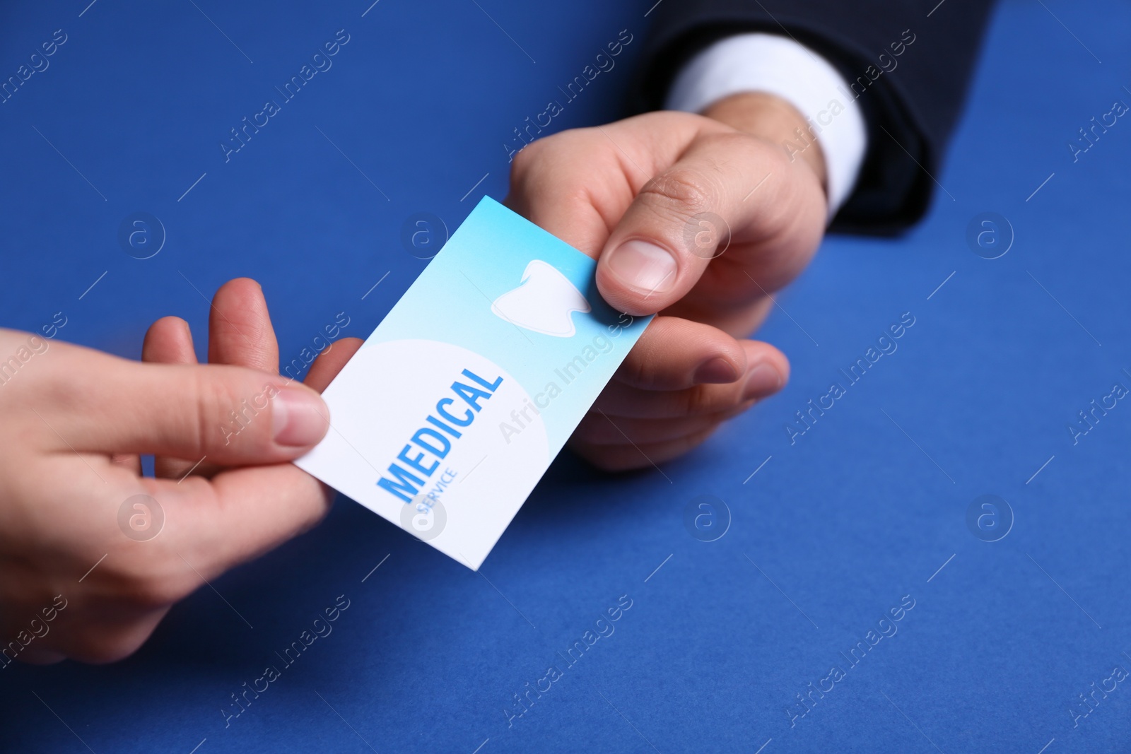 Photo of Man giving business card to woman on color background, closeup. Dental medical service